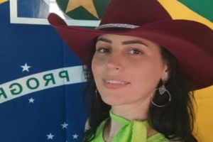 Imagem colorida de Raquel Cattani, filha do deputado estadual Gilberto Cattani (PL), de chapu e com a bandeira do Brasil ao fundo - Metrpoles