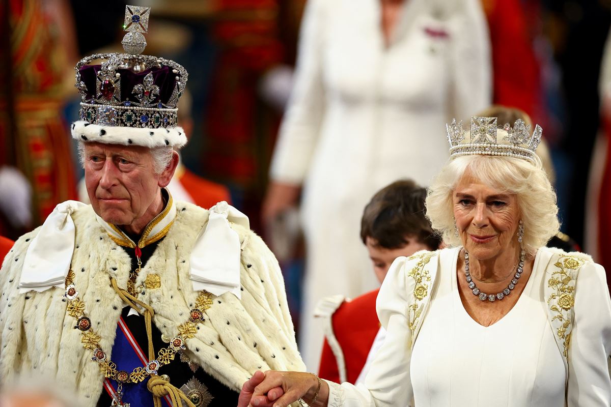 Foto de homem com coroa e manto ao lado de mulher com vestido branco e tiara - Metrópoles