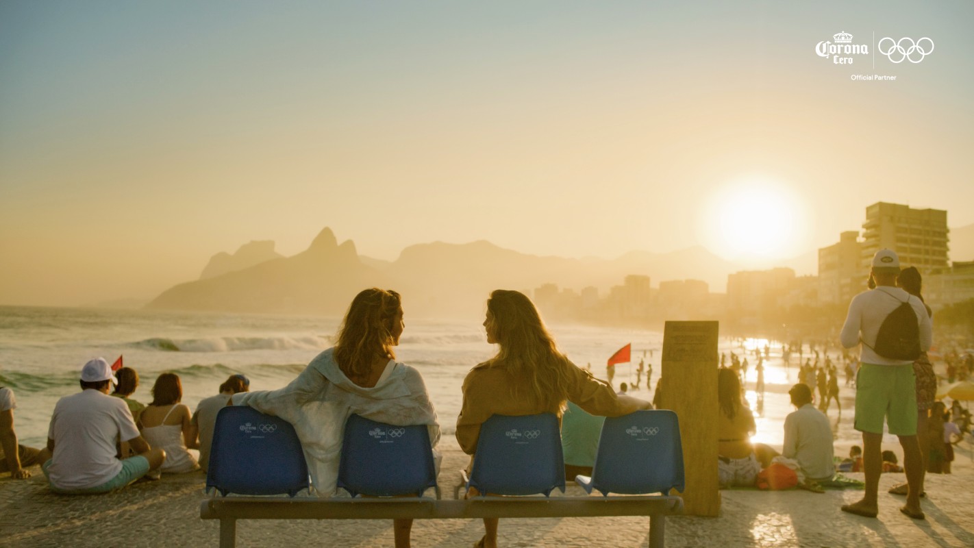 Fotografia colorida mostrando duas mulheres sentadas em banco na orla da praia-Metrópoles