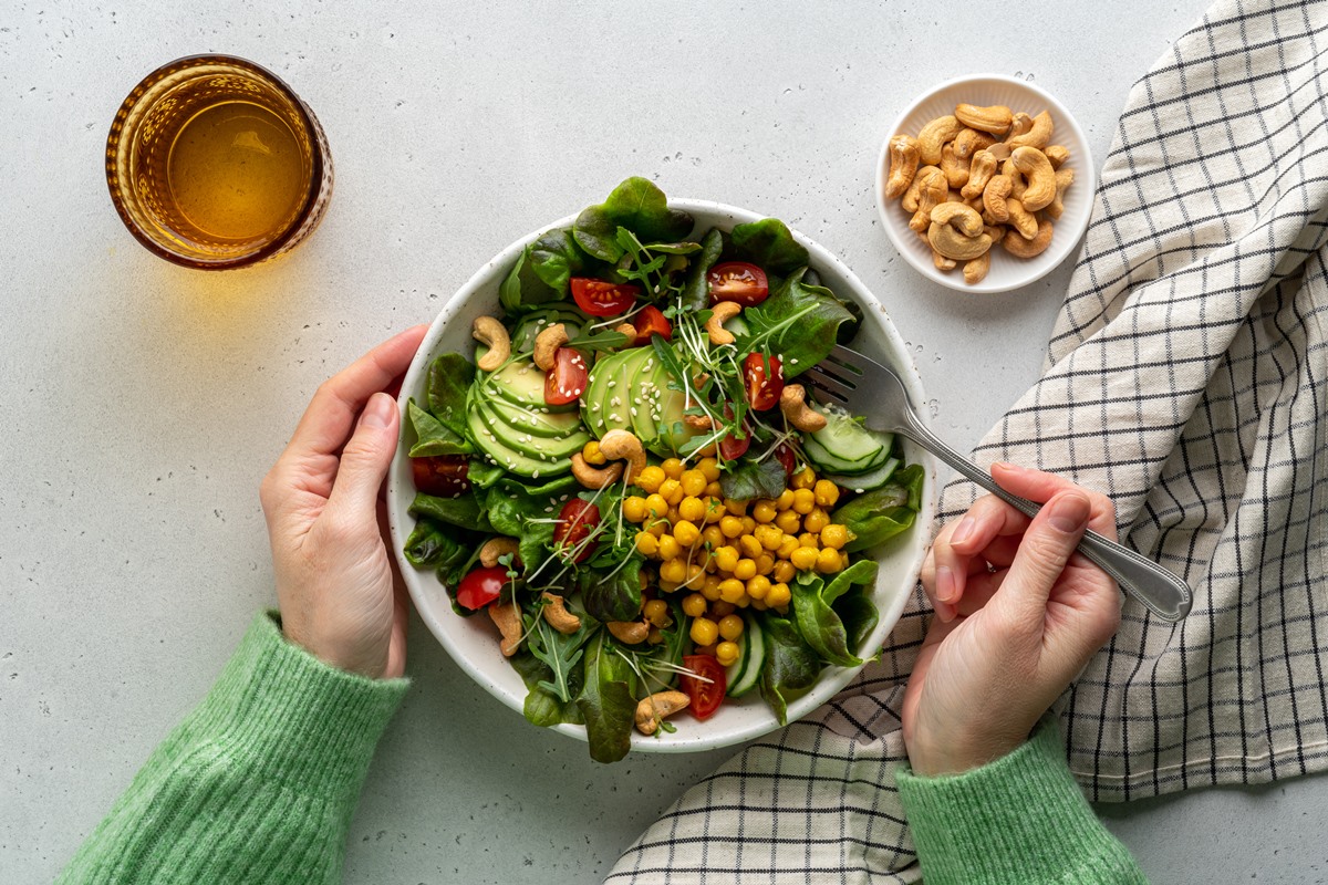 Foto colorida - Prato de salada apenas com alimentos vegetarianos, como tomate, abacate, folhas verdes, castanhas e milho