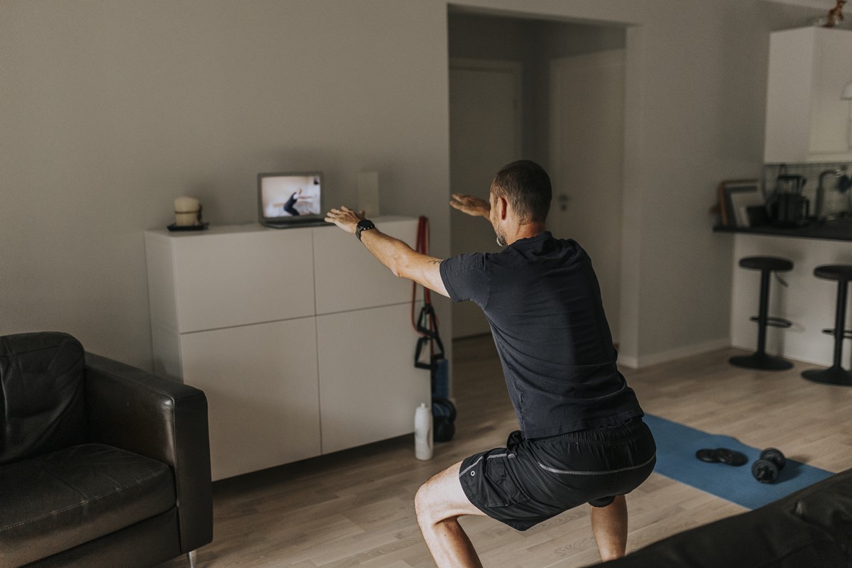 Foto colorida - Homem praticando exercícios em casa