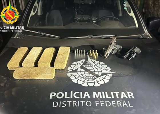 Imagem colorida de drogas e armas em cima de uma viatura - Metrópoles