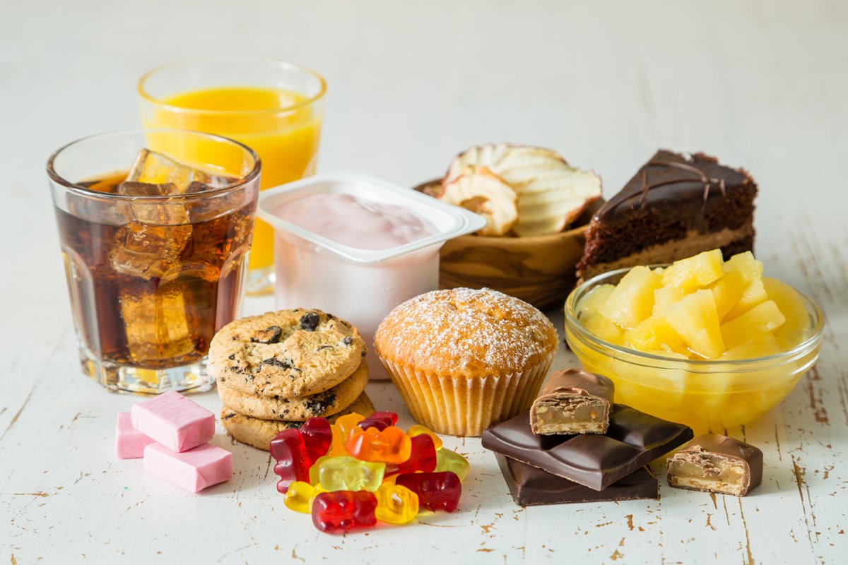 Foto colorida de balinhas, cupcakes, suco, refrigerante, bolo e guloseimas - Metrópoles