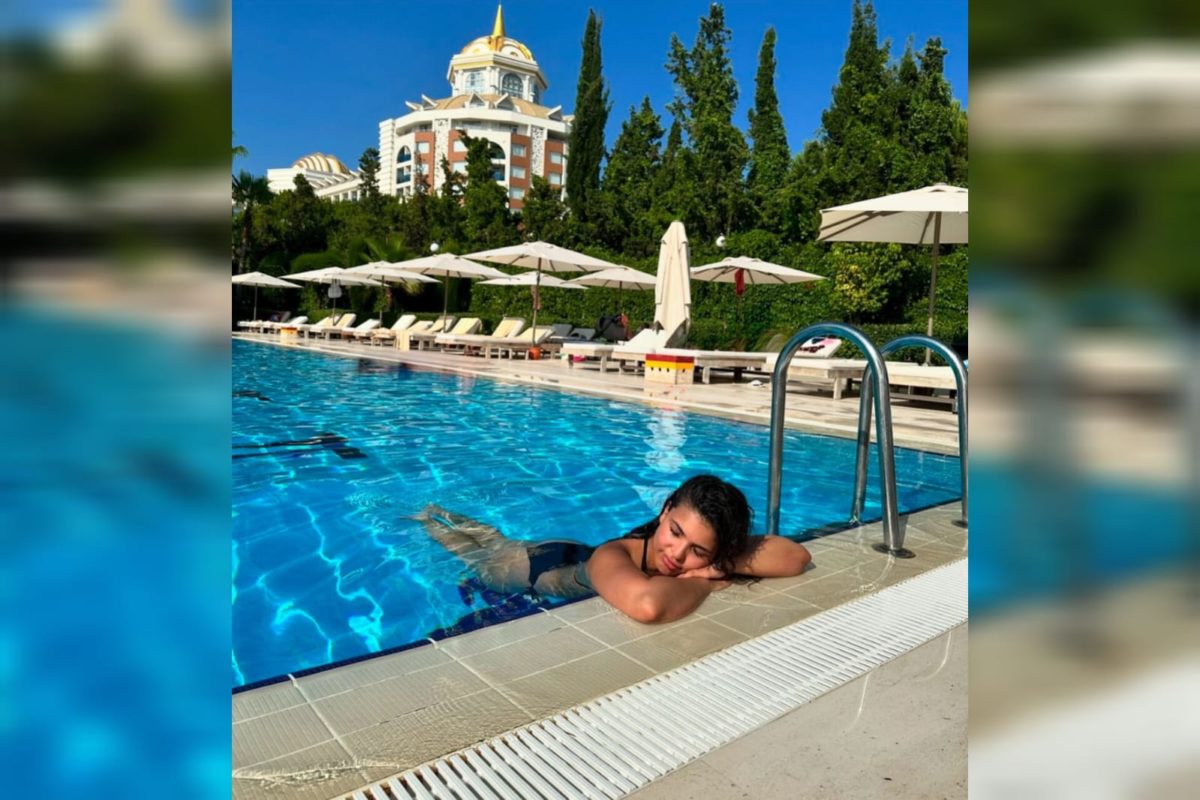 Foto mostra a biomédica inglesa Liana Foster em uma grande piscina de hotel com um edifício ao fundo que teve amigdalite grave por uso de ar-condicionado em hotel