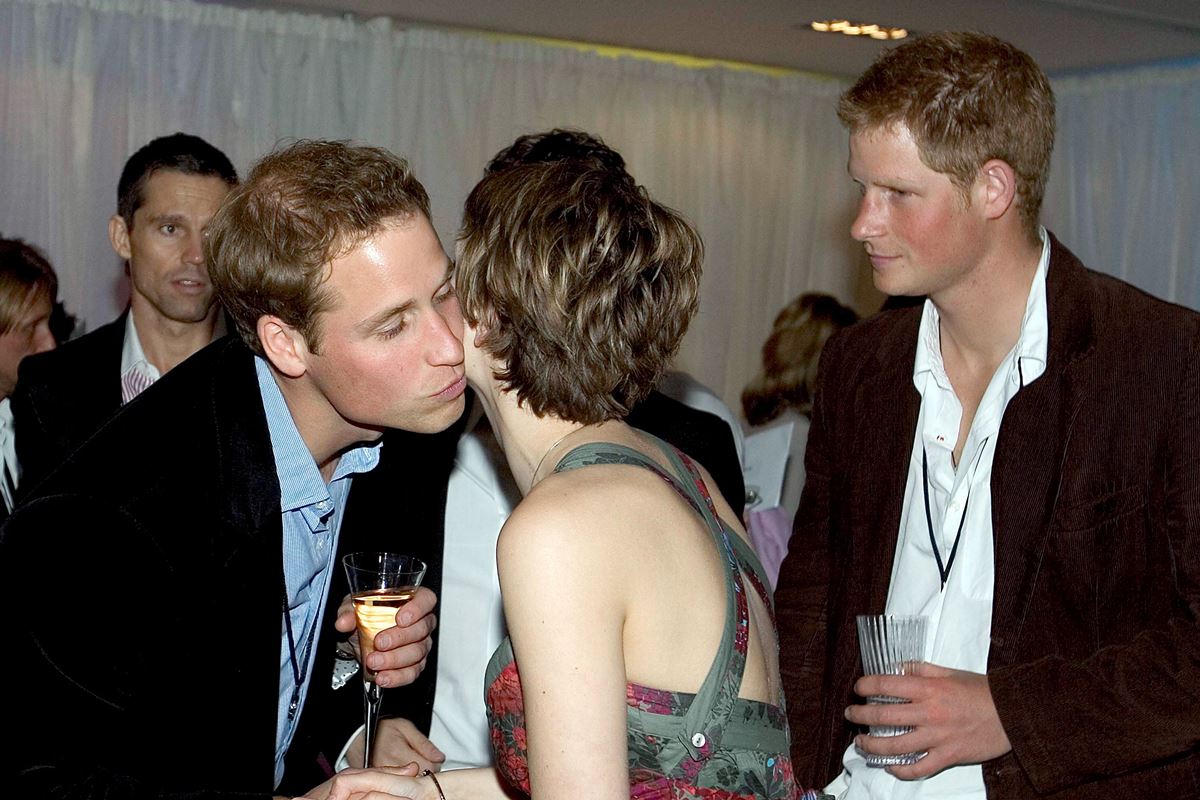 Foto colorida de um homem beijando bochecha de mulher. Um homem ruivo está ao lado - Metrópoles