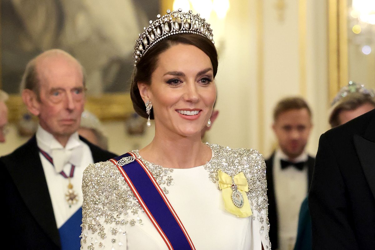 Foto colorida de mulher com tiara na cabeça e roupa branca. Ela usa uma faixa azul - Metrópoles