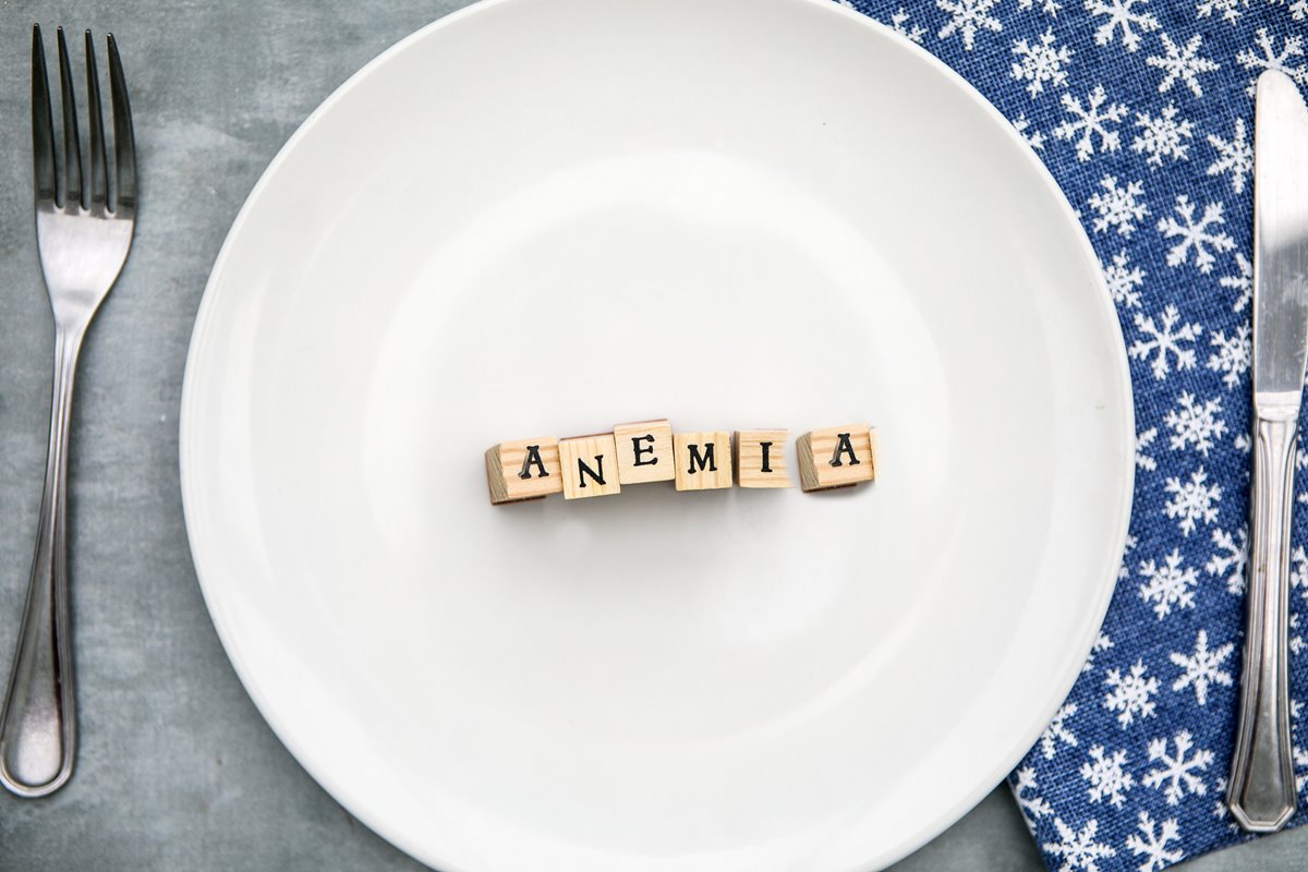 Foto colorida de prato branco com a palavra anemia. Tem um garfo e uma faca ao lado - Metrópoles