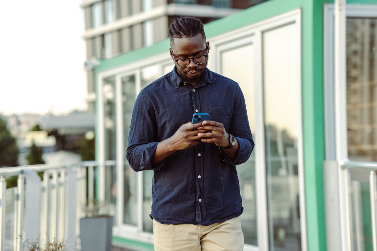 Foto colorida de um homem mexendo no celular - Metrópoles