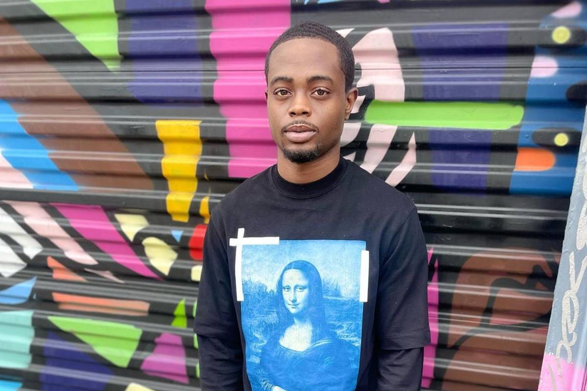 foto colorida de homem negro com blusa preta com desenho da monalisa posando sério - metrópoles