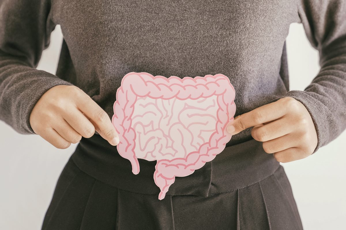 Foto colorida de mulher segurando um papel que representa um intestino - Metrópoles