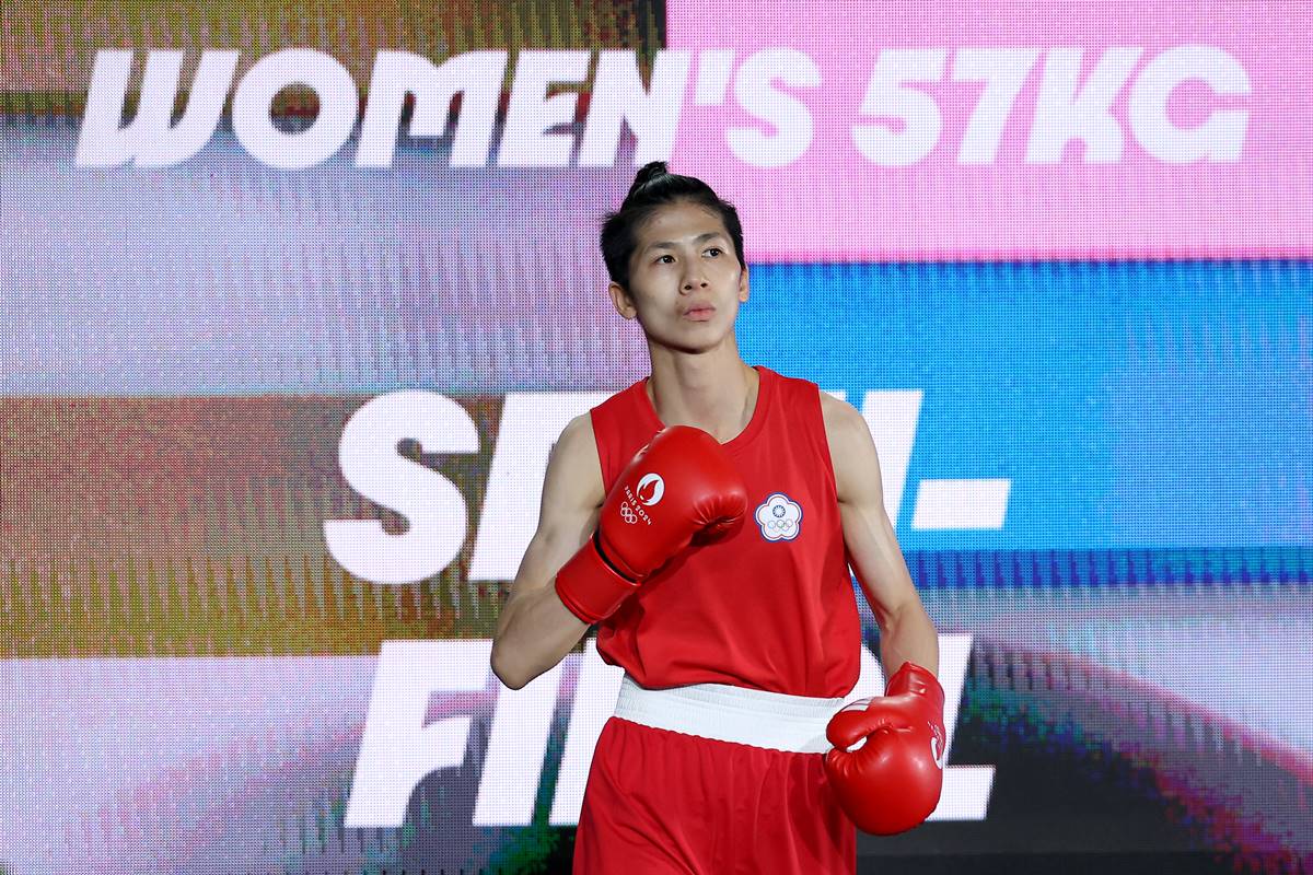 Fotografia mostra a atleta Lin Yu-ting de uniforme vermelho em frente a um painel qu ediz, em inglês, mulheres até 57 kg - Metrópoles