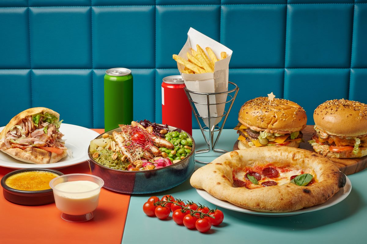 Foto colorida de refrigerantes, batatas fritas, hambúrgueres e pizzas - Metrópoles