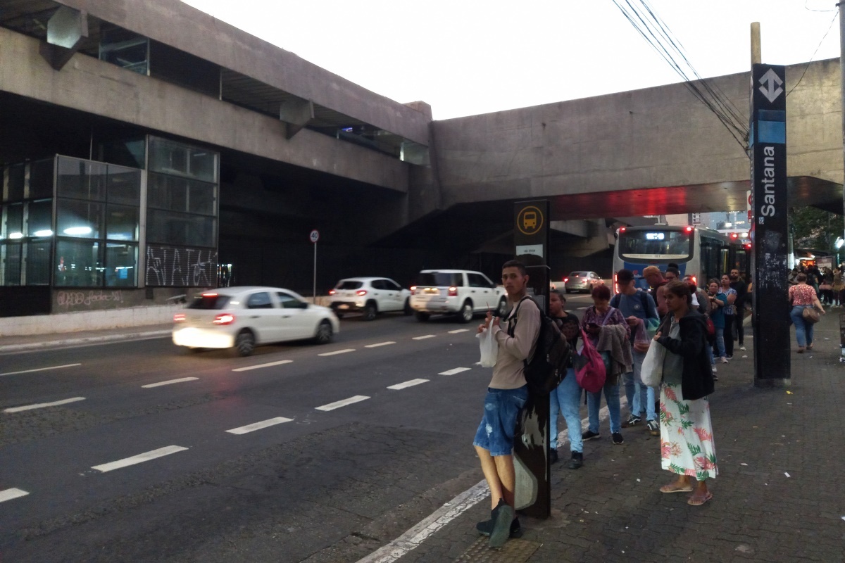 Imagem mostra pessoas em ponto de ônibus