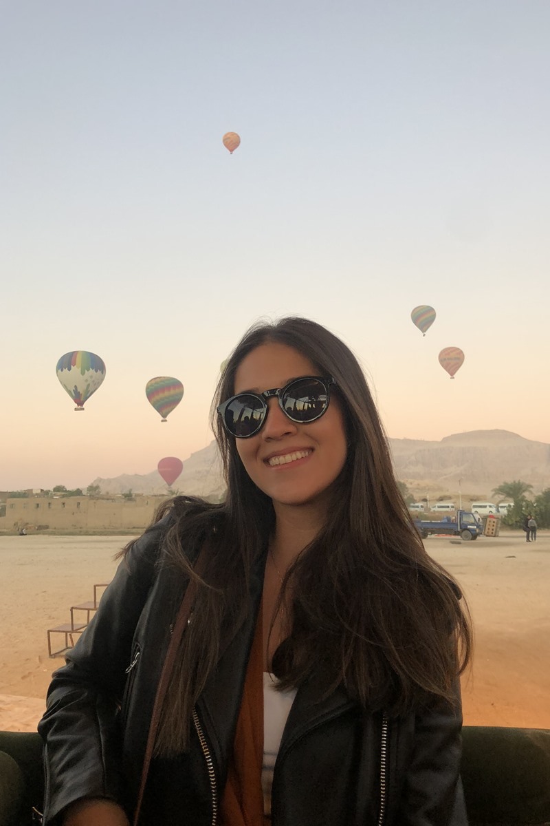 Foto colorida de mulher de óculos escuros perto de um balão - Metrópoles