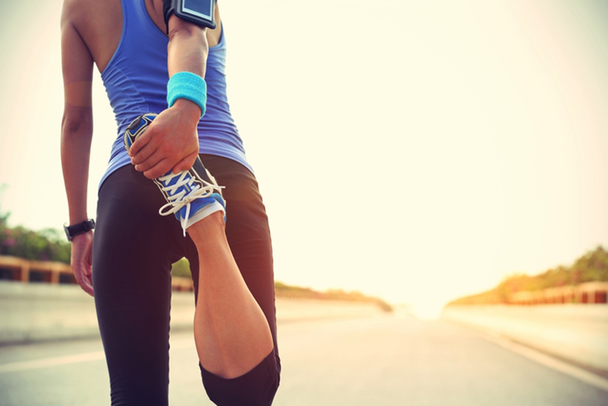 Mulher segura o pé em alongamento para correr ou fazer uma caminhada - metrópoles