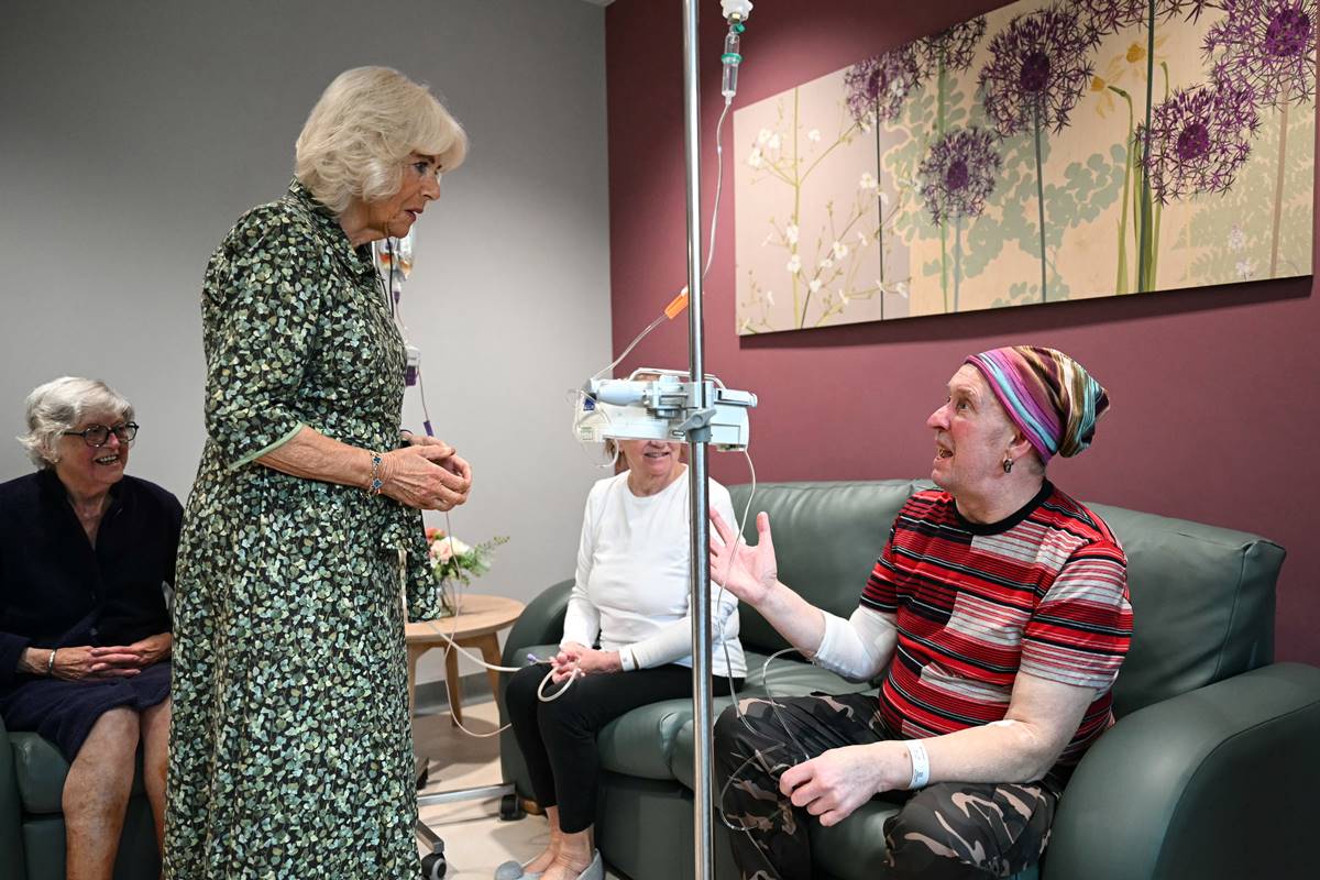 Foto colorida de mulher em pé conversando com pacientes que estão sentados em um sofá - Metrópoles