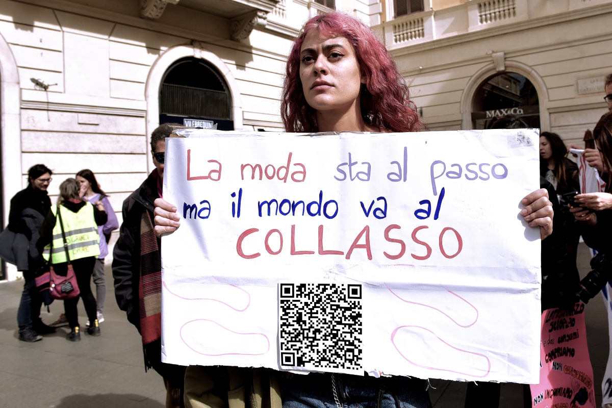 Ativistas do movimento Non Una di Meno com cartazes onde se lê: A moda continua, mas o mundo está em colapso, e faixas nas ruas do centro de Roma contra a exploração no setor da moda durante o dia da greve transfeminista.