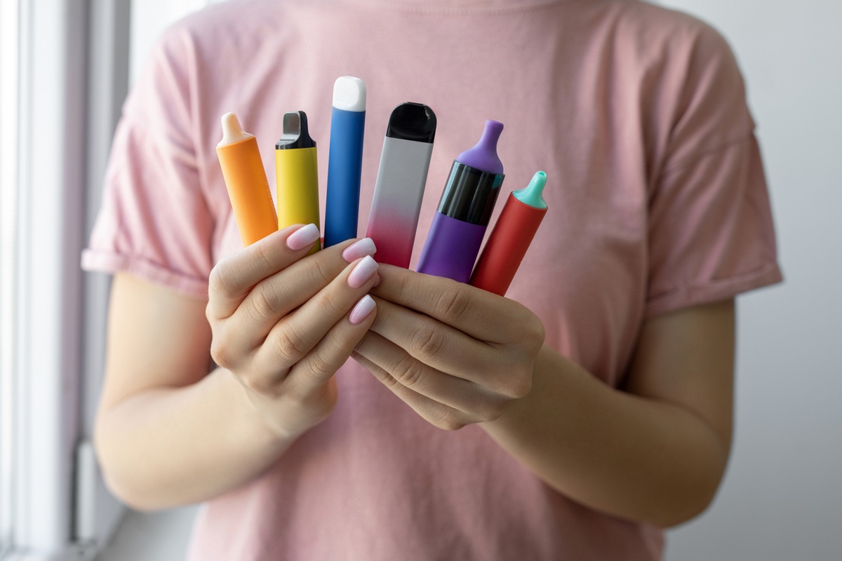 Foto colorida de mão feminina segurando vários tipos de cigarros eletrônicos - Vape