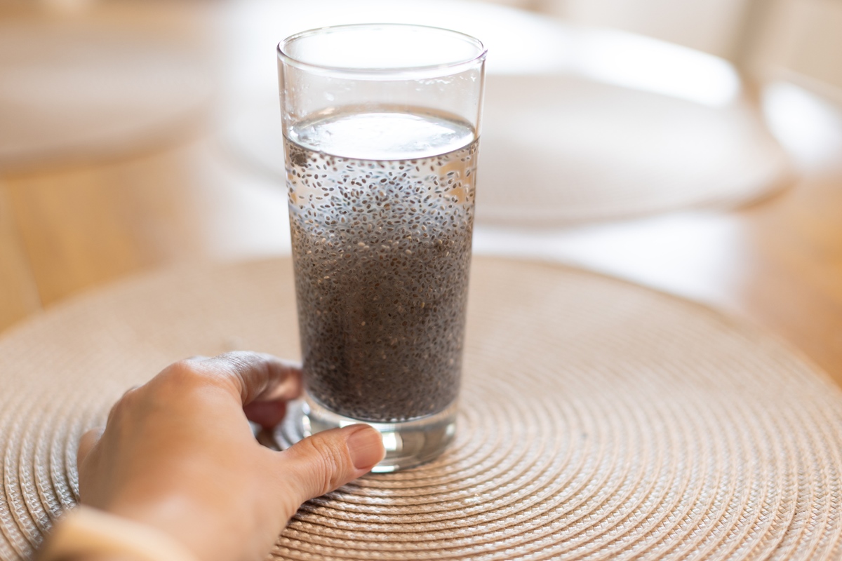 Um copo de água com sementes de chia sobre uma mesa de madeiraChia Seed Water