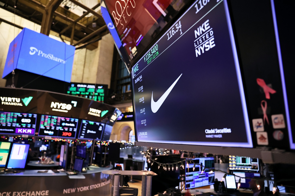 A imagem mostra a logo da Nike transmitida em uma tela em um centro de investimentos com outros dados passando por diversas telas, também exibidas na foto