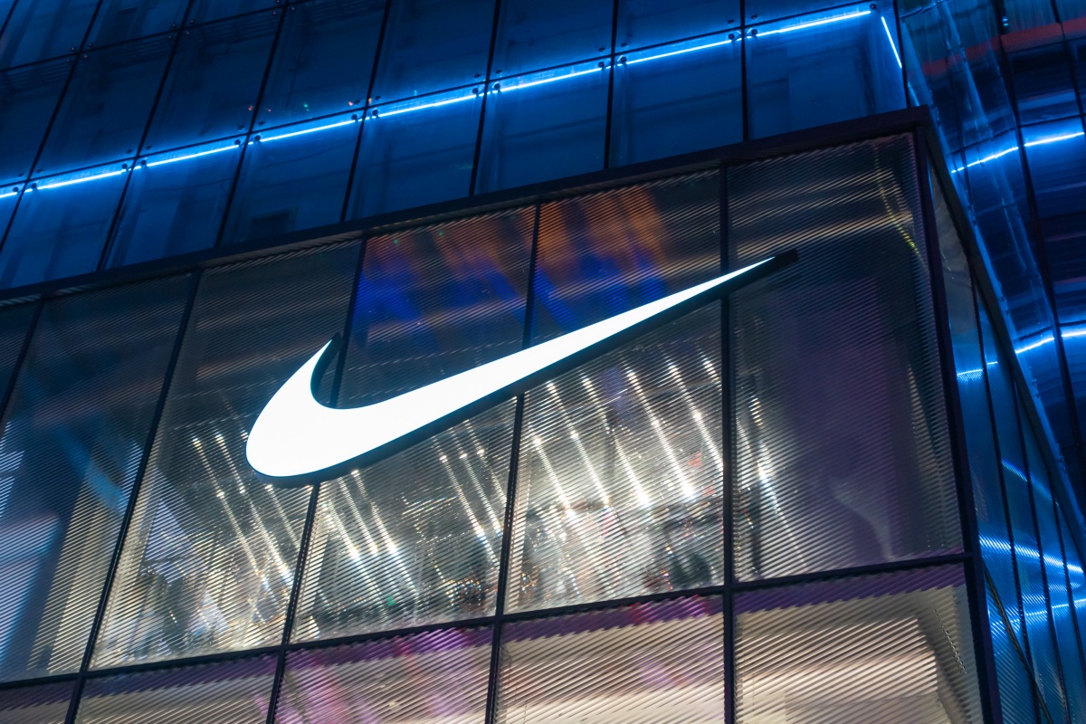 A imagem mostra a logo da Nike sob um edifício espelhado.