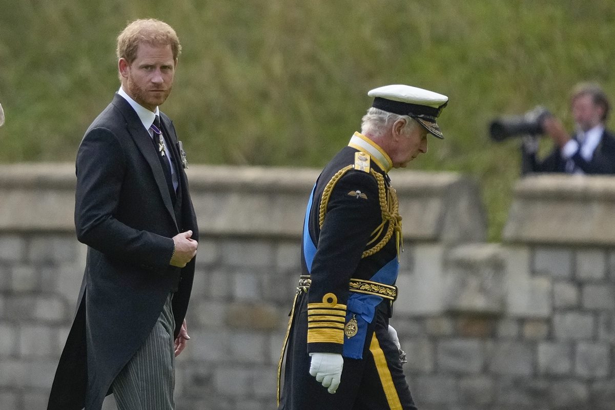 Foto colorida de homem caminhando atrás de homem vestido com traje militar britânico - Metrópoles