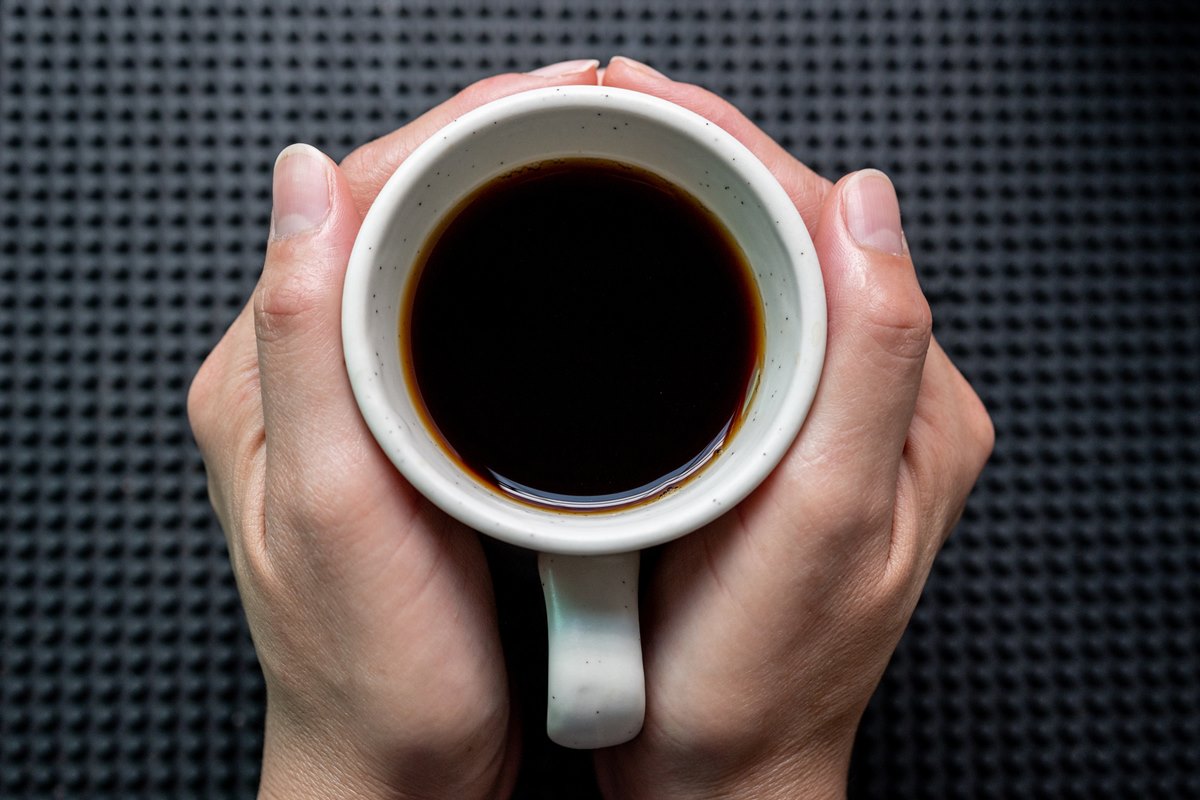 Foto colorida de mãos feminina segurando uma xícara de café - Metrópoles