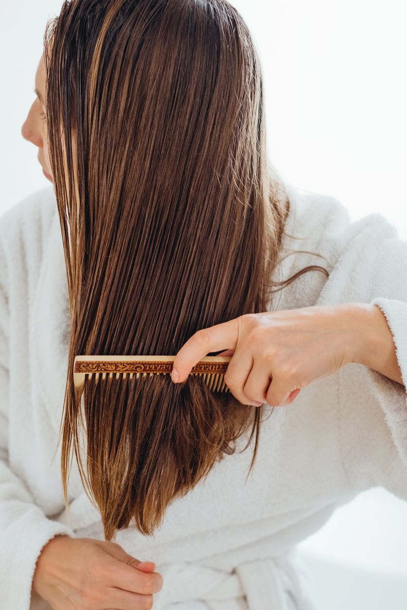 Foto colorida - Mulher penteando o cabelo 