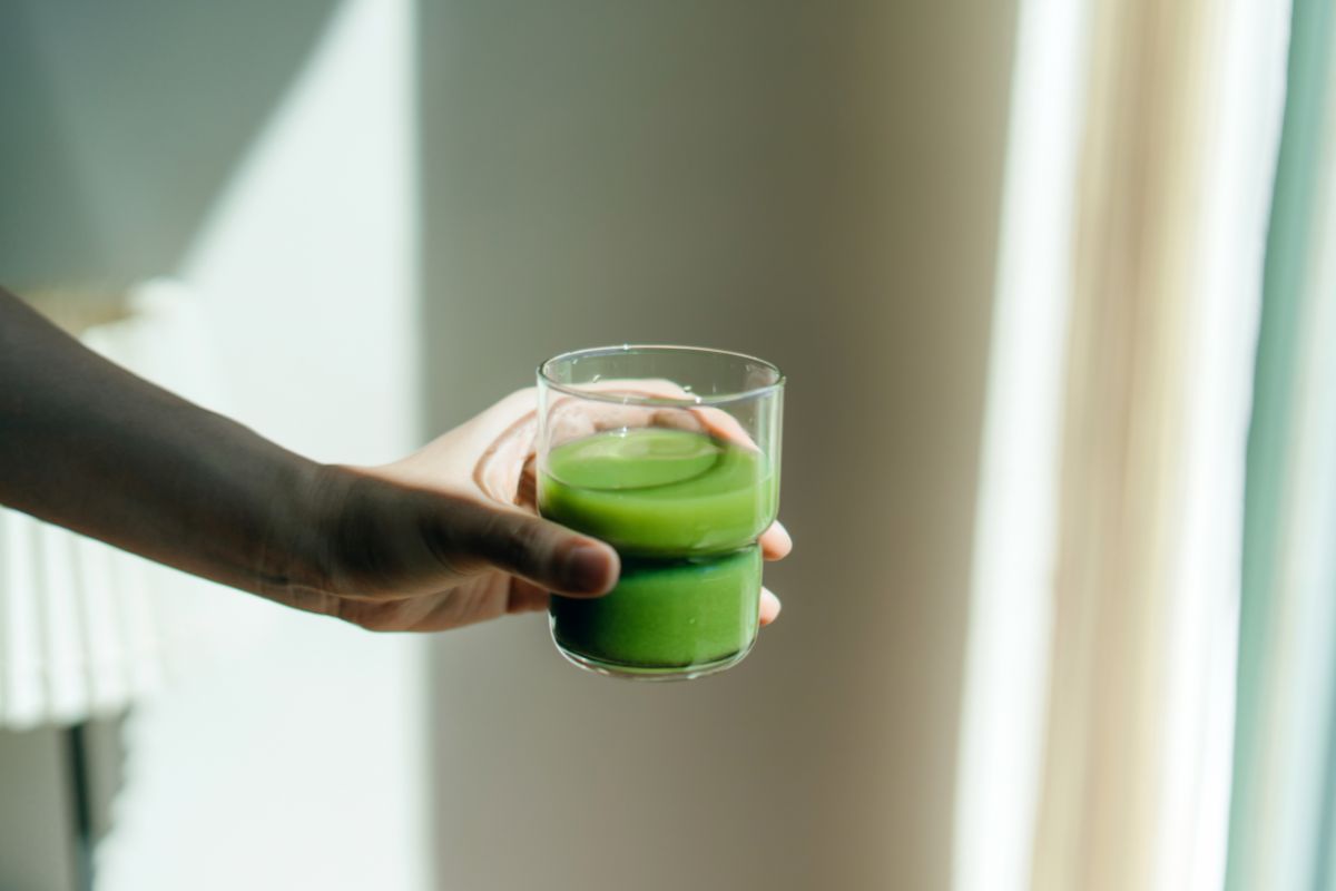 pessoa segurando um copo de suco verde, couve, ora-pro-nóbis