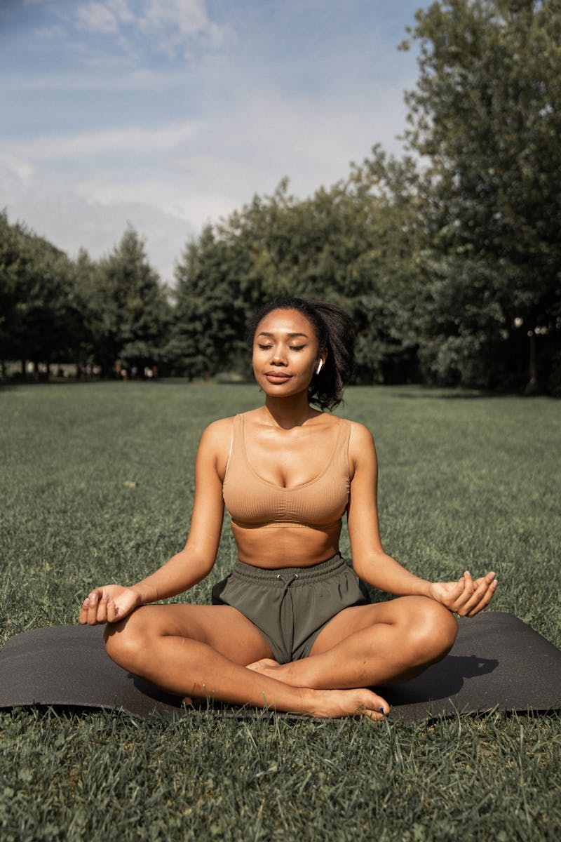 Jovem mulher negra meditando no gramado - Metrópoles