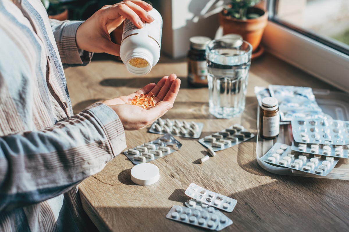 Closeup mão feminina colocando ordenadamente o medicamento na vista superior do kit de primeiros socorros doméstico. - Metrópoles