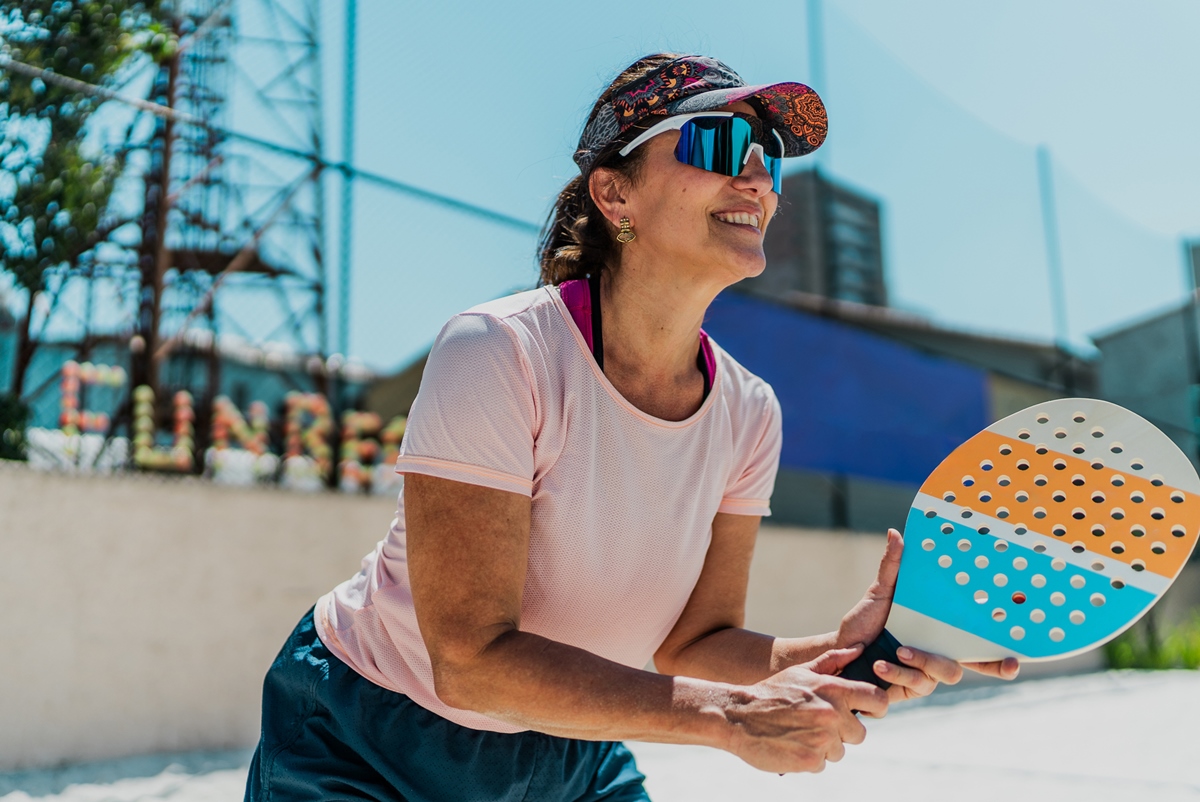 Mulher madura jogando beach tennis em quadra - Metrópoles