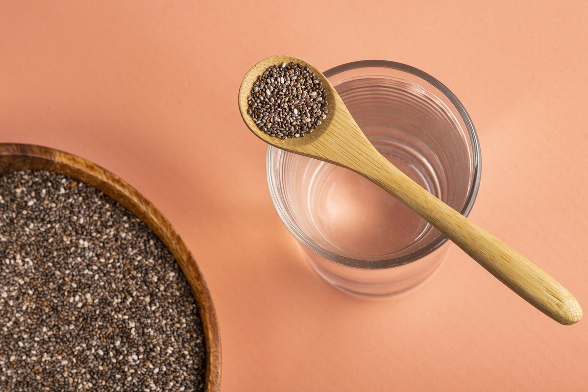 Foto colorida de tigela e colher com chia. A colher de pau está em cima de um copo com água - Metrópoles