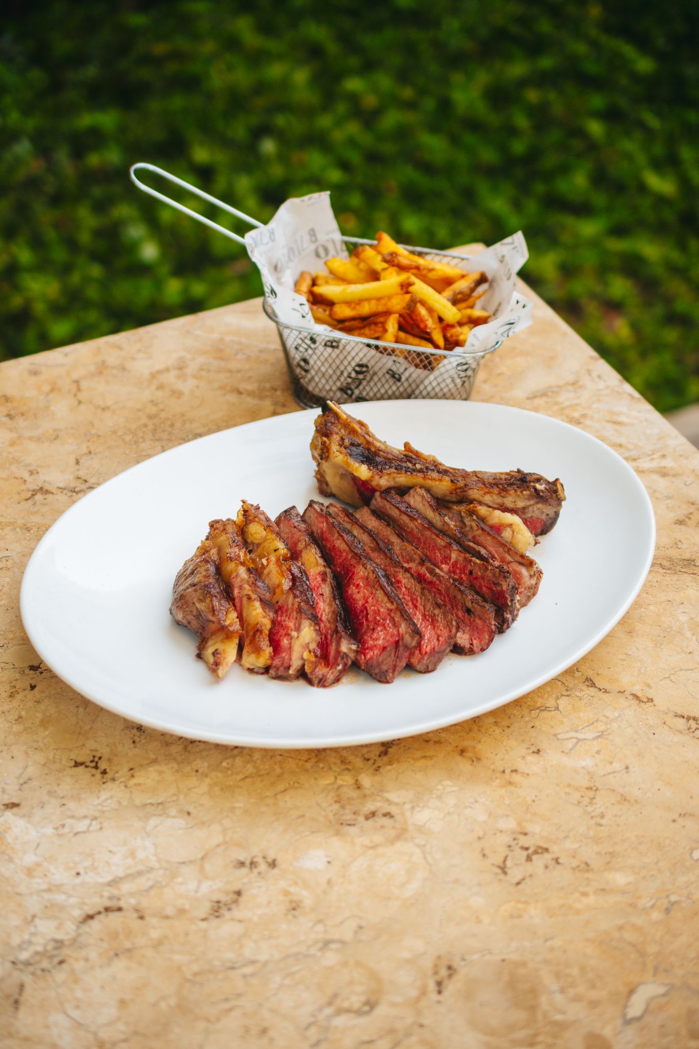 Na imagem colorida, carne vermelha fatiada servida com batatas fritas; os dois dispostos em uma mesa - Metrópoles 