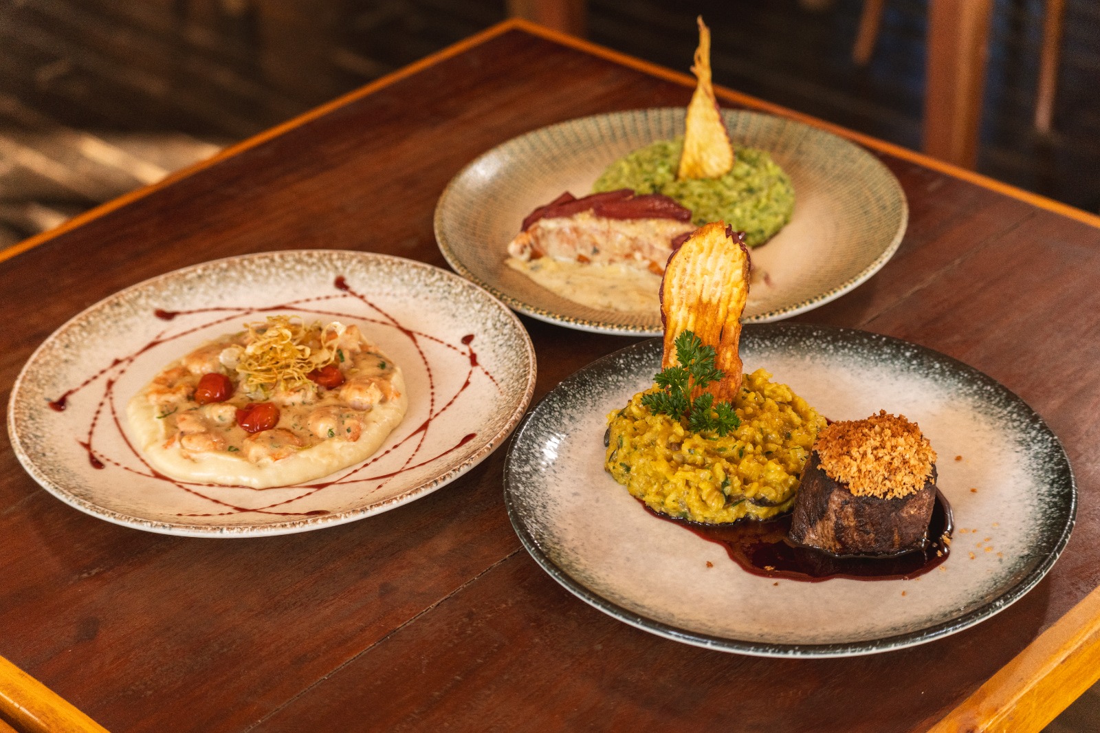 Na imagem colorida, três pratos do menu primavera do Dudu Bar dispostos em uma mesa - Metrópoles 