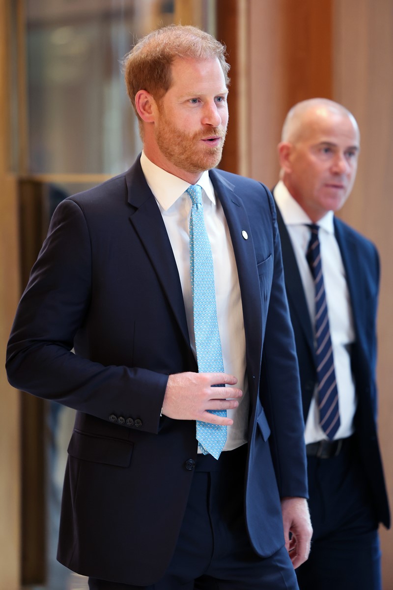 Foto colorida de homem, ruivo e de blazer azul-escuro, andando. Atrás dele, há outro homem de terno - Metrópoles