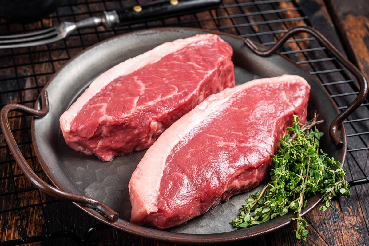 Foto colorida de dois bifes de carne bovina em uma panela - Metrópoles