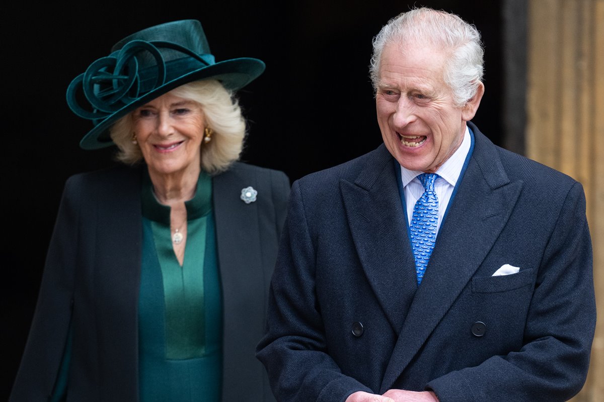 Foto colorida de mulher com roupa verde e blazer preto ao lado de homem com casaco preto e gravata azul. Os dois estão rindo - Metrópoles