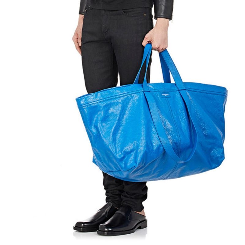 A imagem mostra uma mão masculina segurando uma bolsa azul