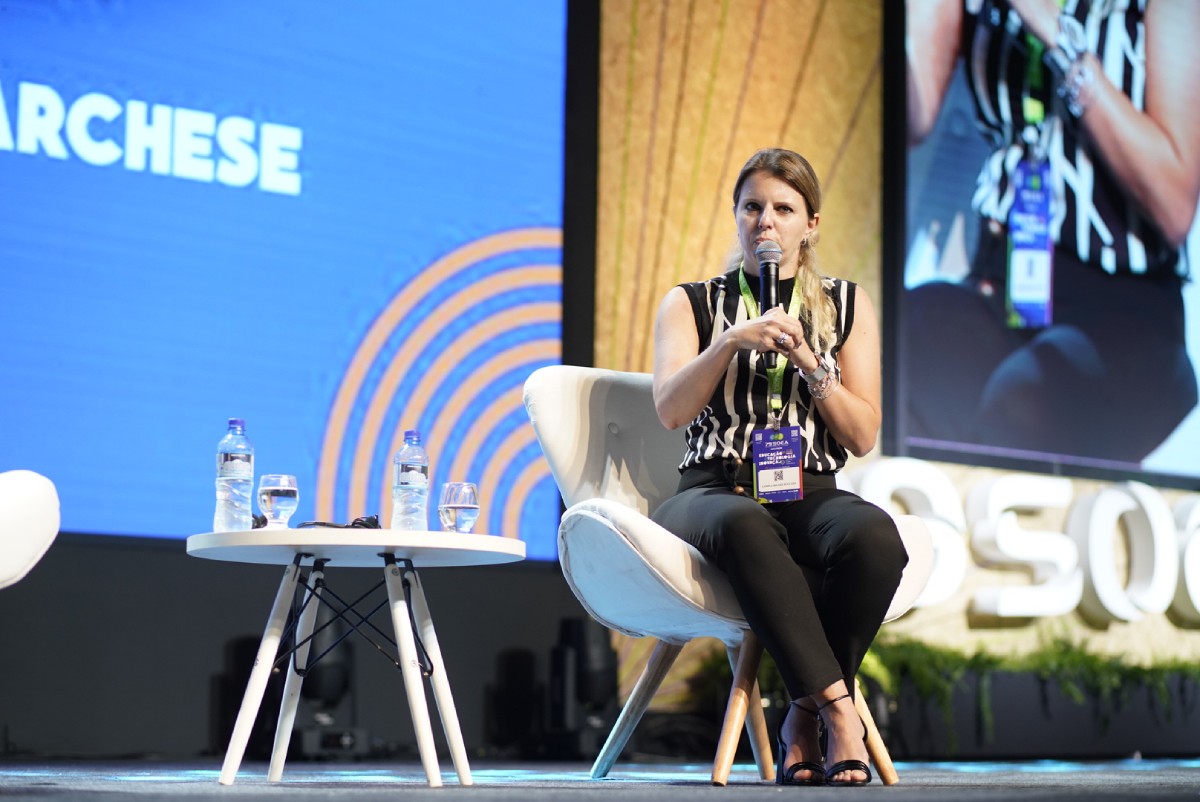 Fotografia colorida mostrando mulher sentada em palco discursando-Metrópoles