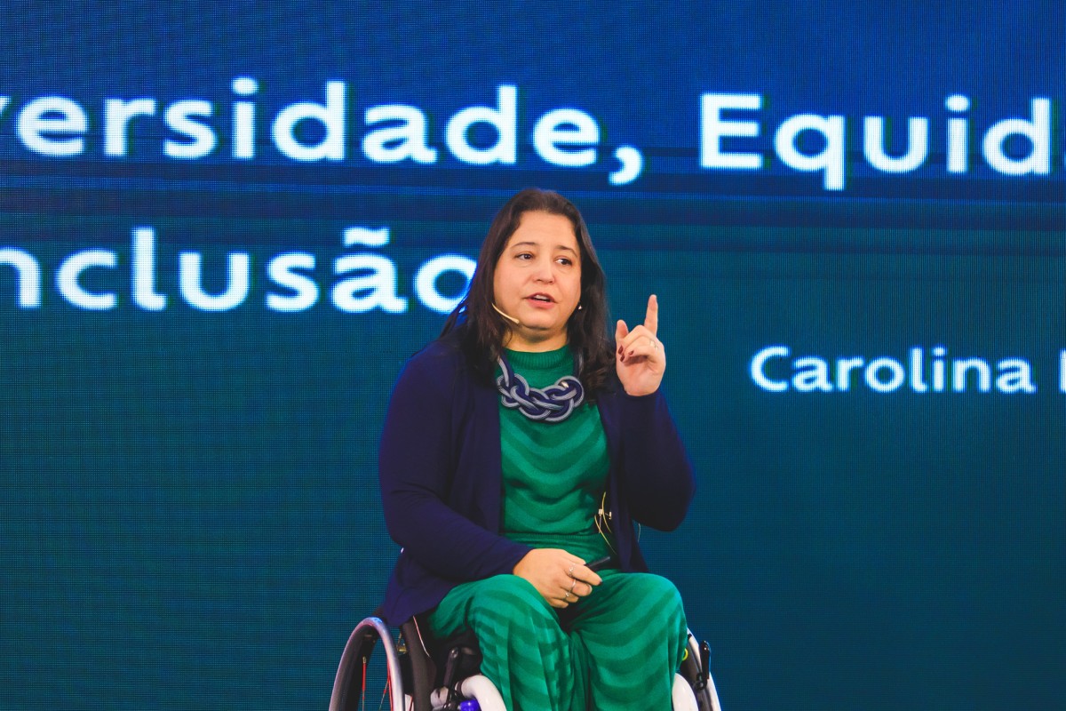 Fotografia colorida mostrando mulher em palco discursando em cadeira de rodas-Metrópoles