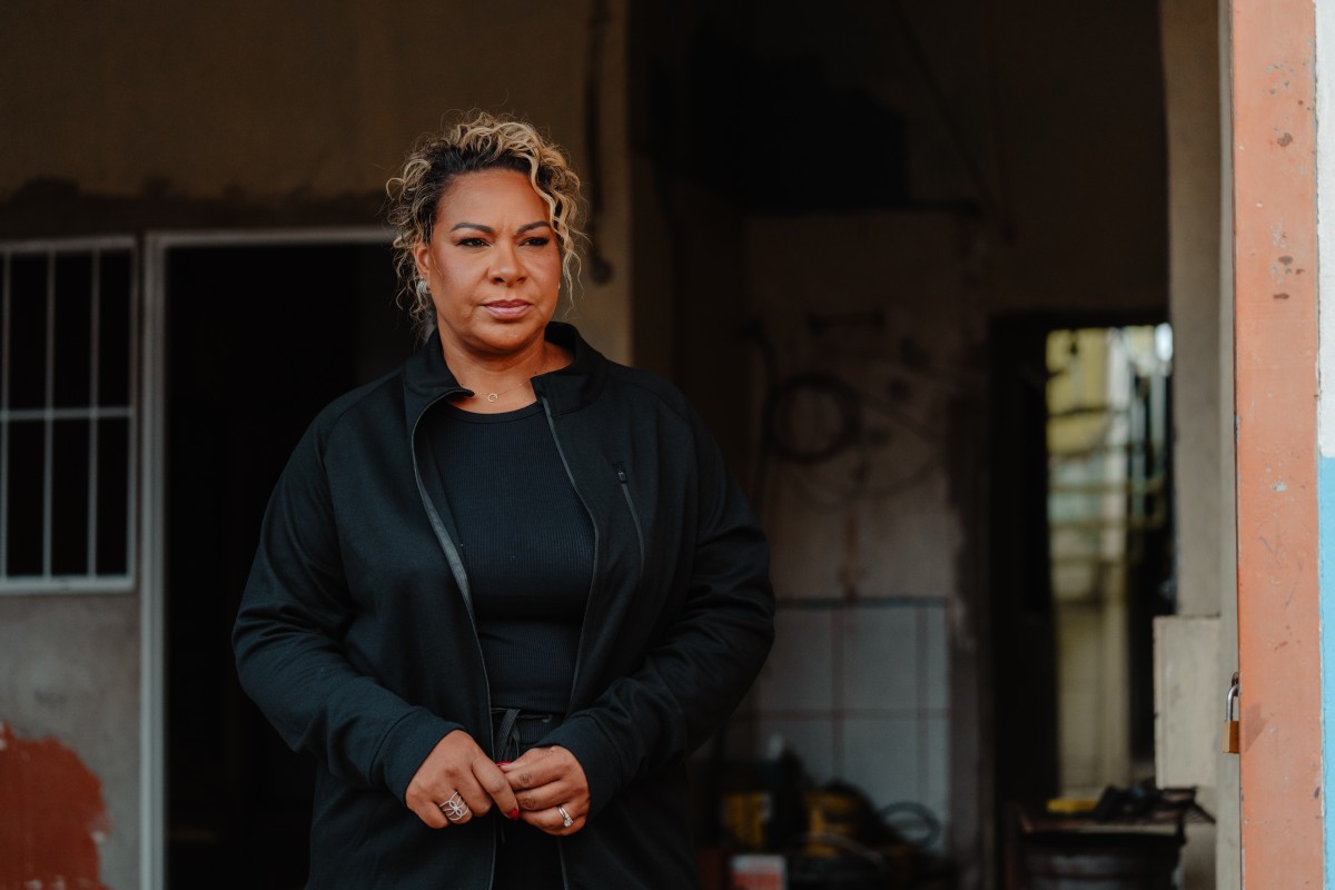 Fotografia colorida mostrando mulher dentro de casa próxima do portão-Metrópoles