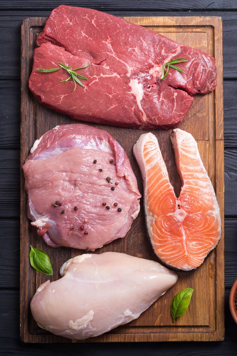 Foto colorida de carnes de peixe, frango, bovina e suína em cima de uma tábua - Metrópoles