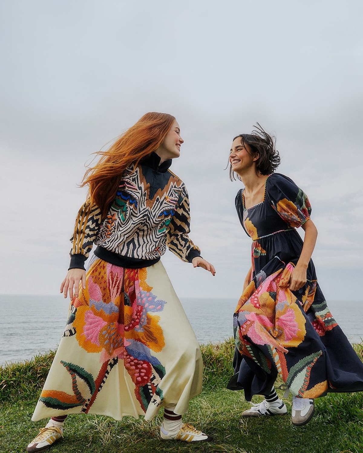 A imagem mostra duas mulheres sorrindo enquanto se divertem vestindo peças coloridas nas cores preto, branco, amarelo, azul e outras tonalidades