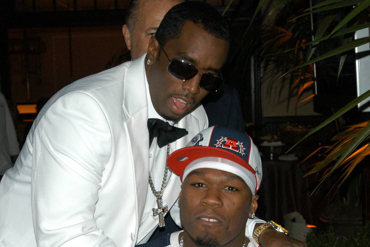 Na imagem colorida, 50 Cent e Sean Diddy Combs aparecem lado a lado. Diddy usa terno branco e óculos, e 50 Cent posa de boné - Metrópoles