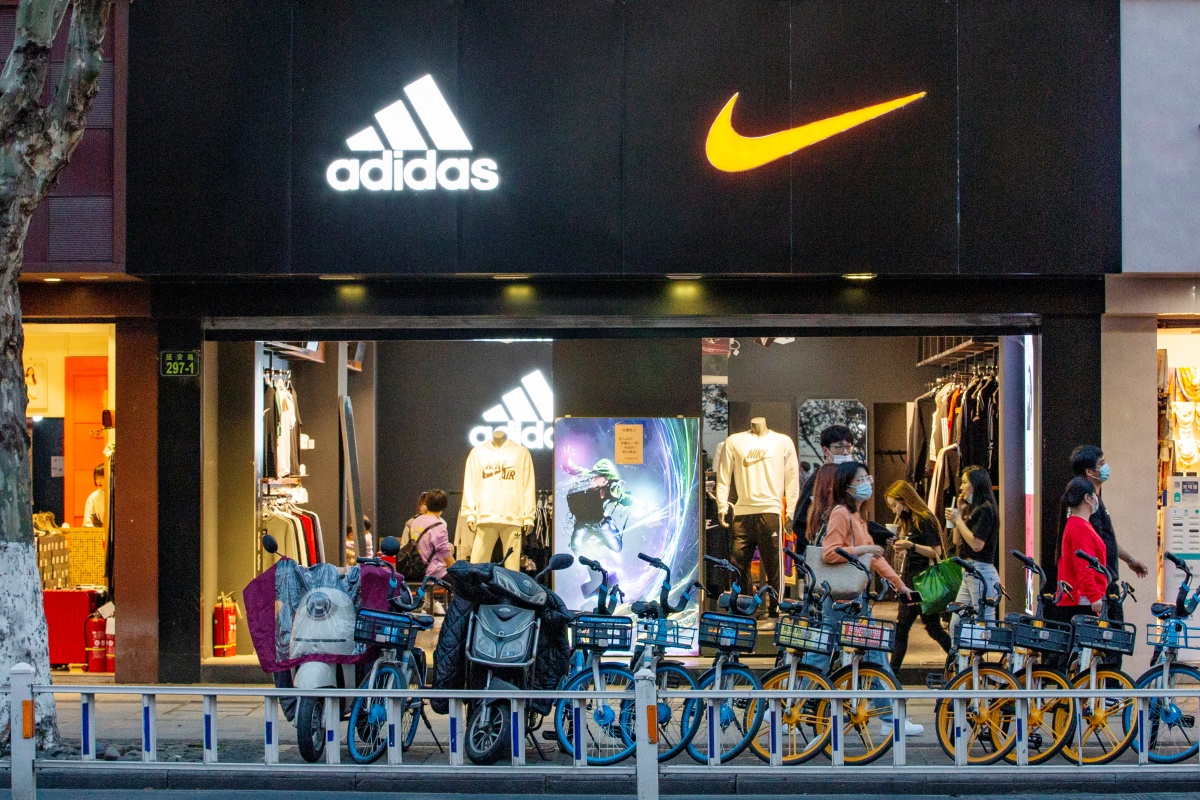 A imagem mostra a faixada de uma loja com as logos da Nike e Adidas lado a lado