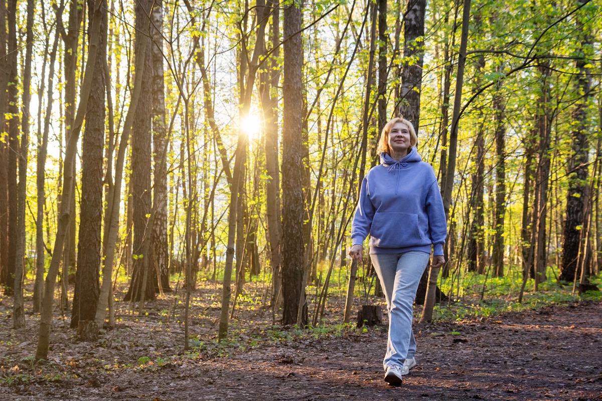 Mulher caminhando em um parque iluminado pelo sol ao pôr do sol na primavera - Metrópoles