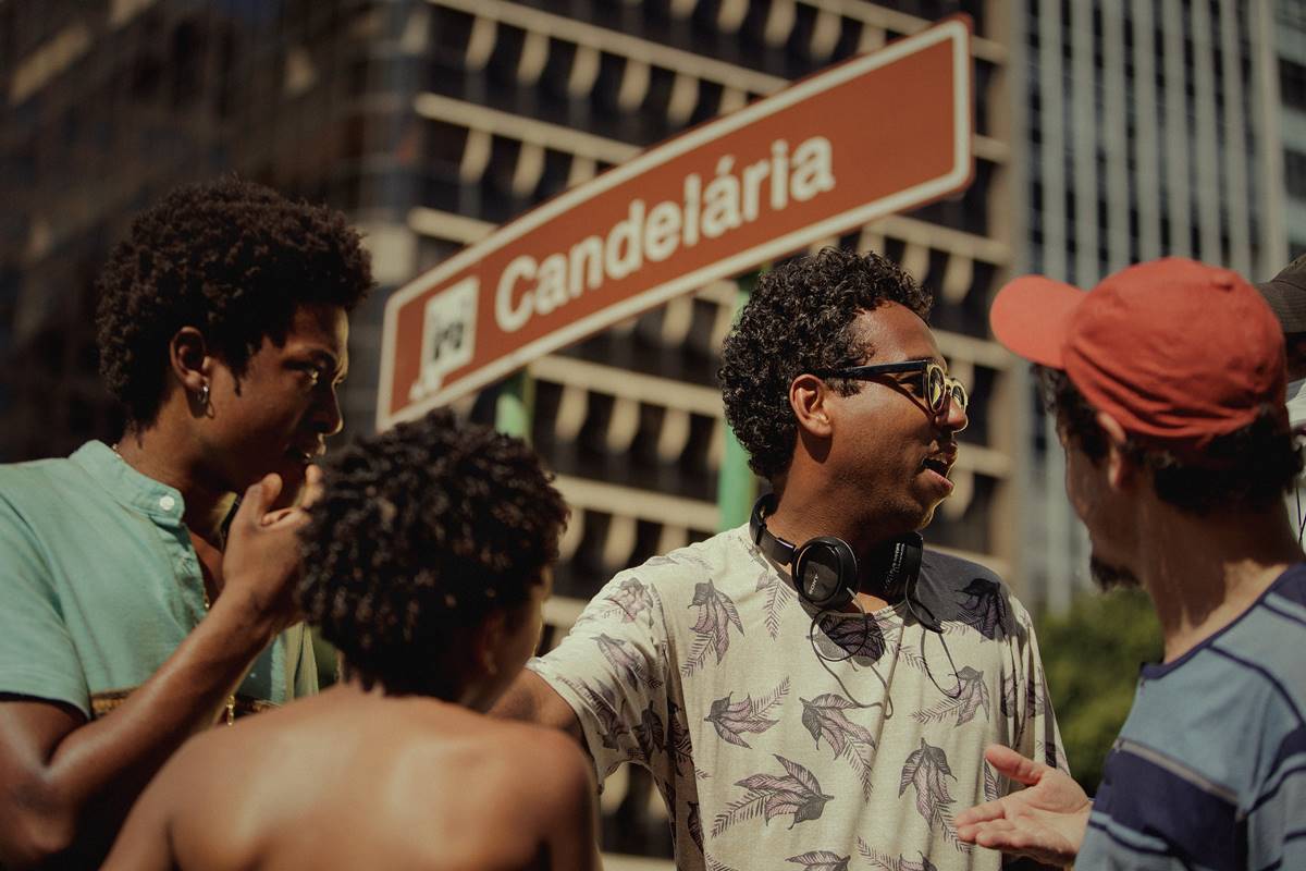 Imagem colorida de Luis Lomenha nos bastidores de Os Quatro da Candelária, ao lado dos atores da série - Metrópoles