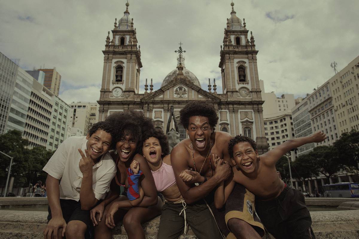 Imagem dos bastidores de Os Quatro da Candelária, mostra quatro meninos sorrindo em frente a igreja - Metrópoles