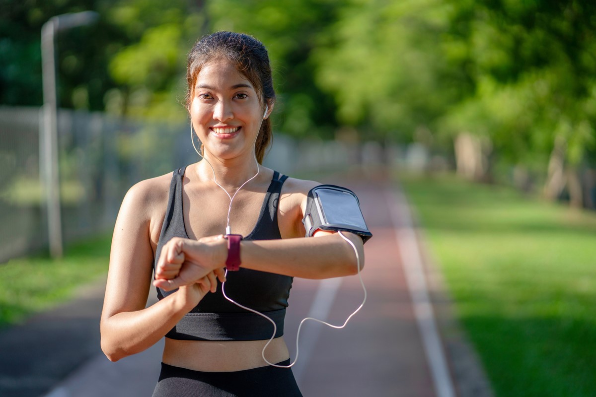 Foto colorida de mulher fazendo caminhada e olhando o smartwatch - Metrópoles